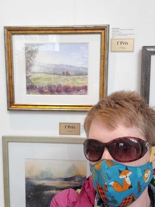 Sandra with her First Prize painting, wearing a cartoon mask